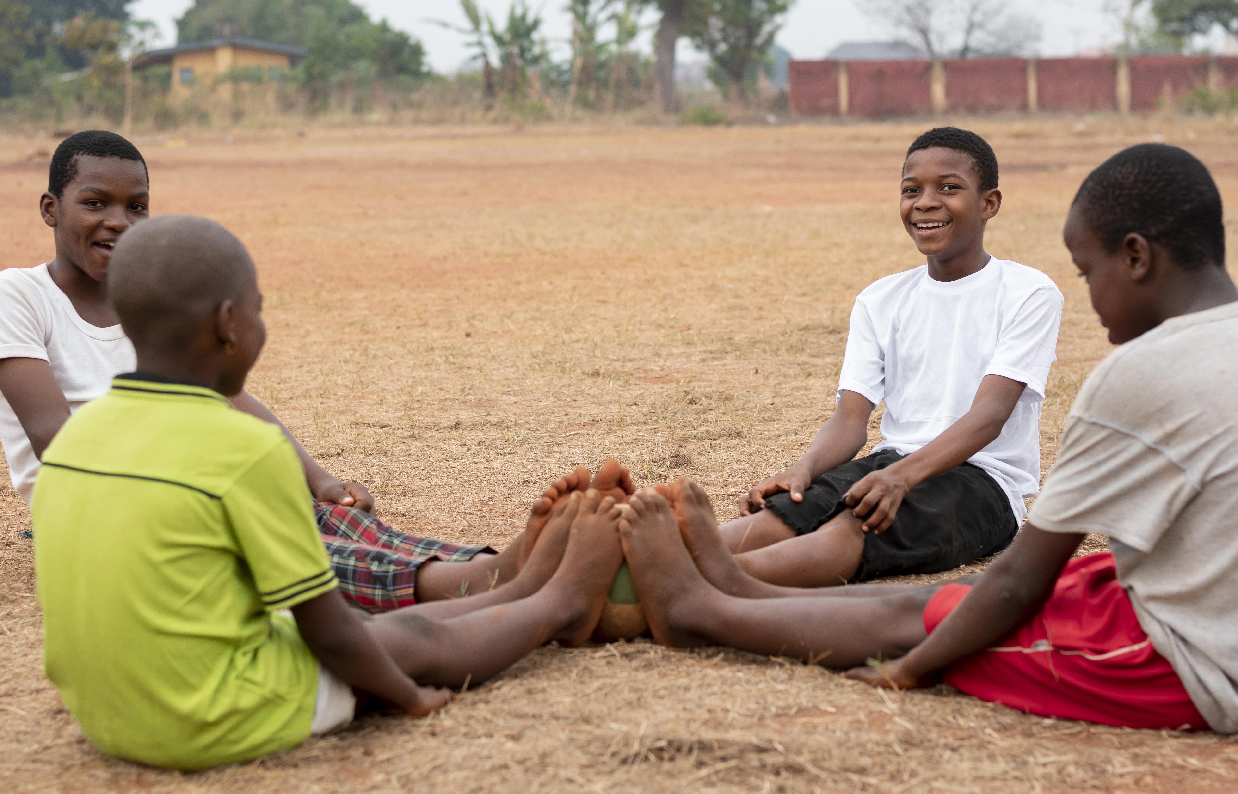 Children sitting together with a football, ready to play.